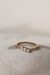 Juliette three pearl ring in gold resting on a pale stone