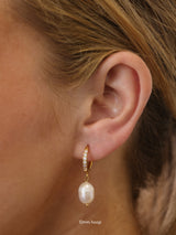 Three sizes of gold pavé waterproof hoop earrings with natural freshwater pearl drops displayed on a textured neutral background