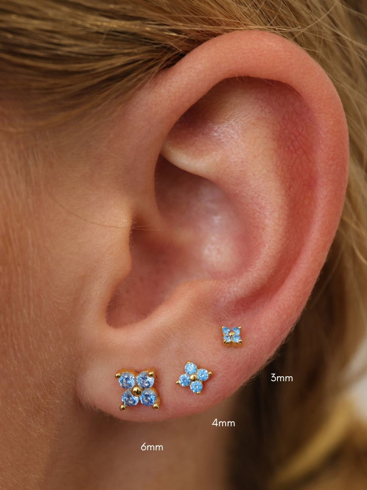 Size guide showing gold 4 clover blue stud earrings in 3mm, 4mm and 6mm on a model's ear