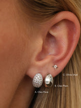 Close-up of a person's ear showing three stud earrings labeled A. Cleo Pave, B.