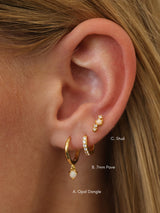 Gold opal set worn on one ear and labelled A. Opal Dangle, B. 7mm pavé huggie and C. Opal stud.
