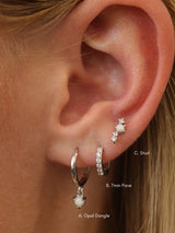 Silver opal set worn on one ear and labelled A. Opal Dangle, B. 7mm pavé huggie and C. Opal stud.