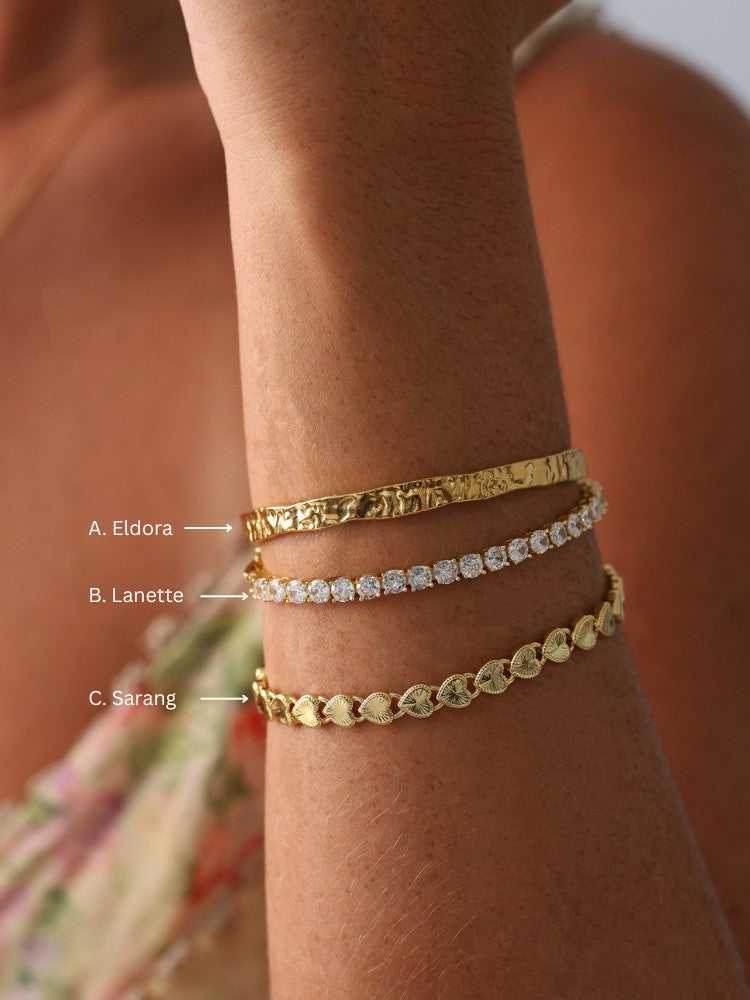 Triple gold and silver bracelet stack featuring hammered bangle, CZ tennis bracelet, and heart-link chain—elegant holiday gift for her