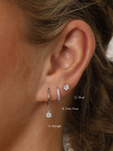 A three‑pair sterling silver earring set featuring a CZ dangle earring, a small cubic zirconia huggie hoop, and a delicate CZ stud. All pieces are rhodium‑plated 925 sterling silver, hypoallergenic, nickel‑free, and displayed together as a coordinated trio.