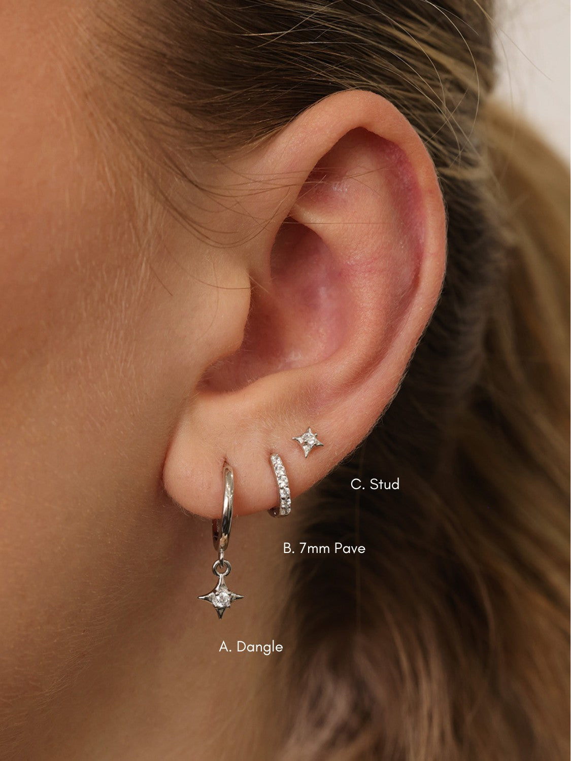 A three‑pair celestial silver earring set featuring a star stud, a moon‑shaped huggie, and a sparkling dangle charm, displayed together for an elegant, versatile look.