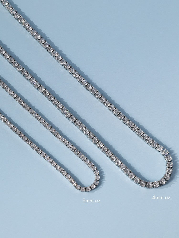 Two silver tennis chains laid diagonally on a light blue background, labelled 3mm and 4mm chain widths.