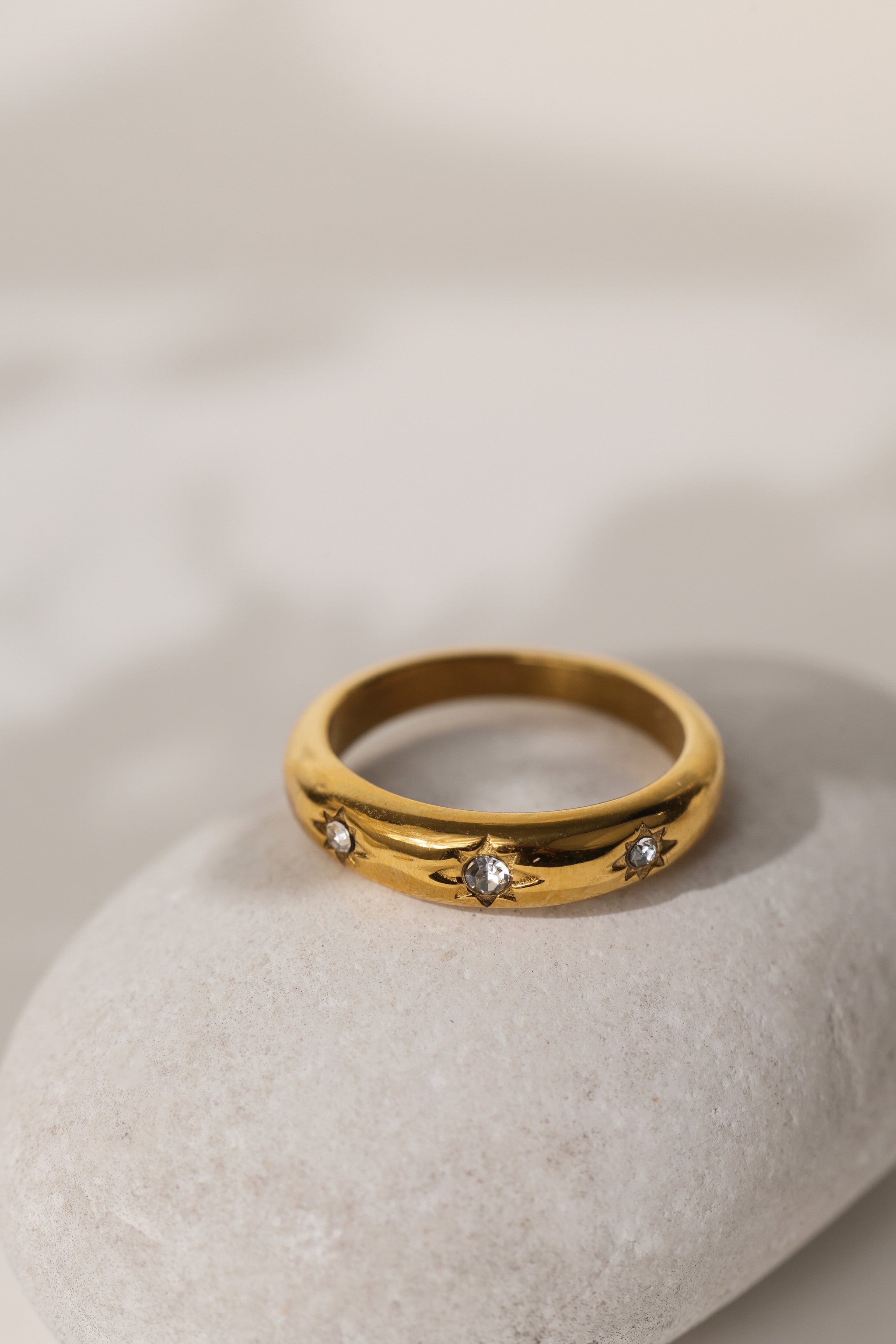 Camille star dome ring in gold resting on a pale stone
