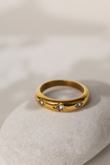 Camille star dome ring in gold resting on a pale stone