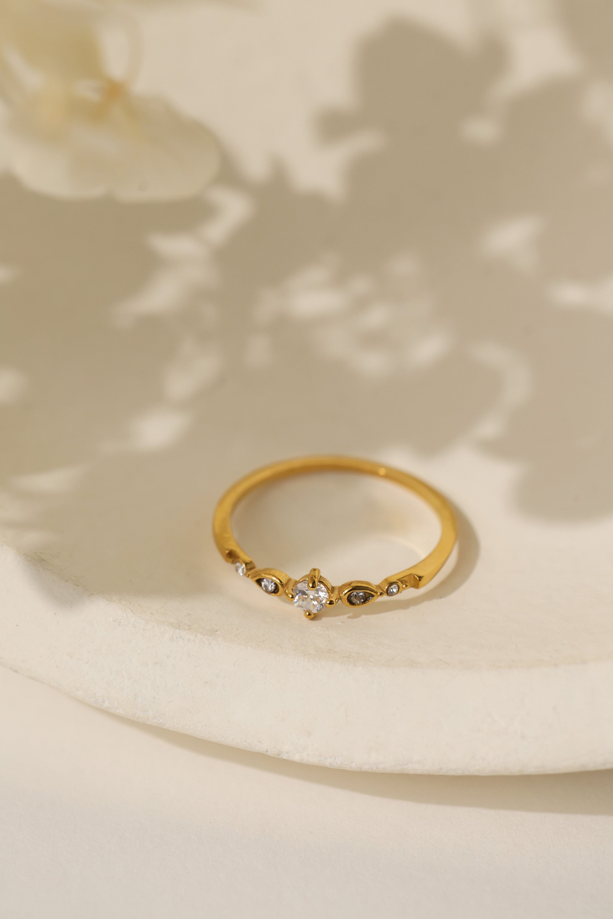Colette vintage five stone ring in gold on a cream dish with soft shadow