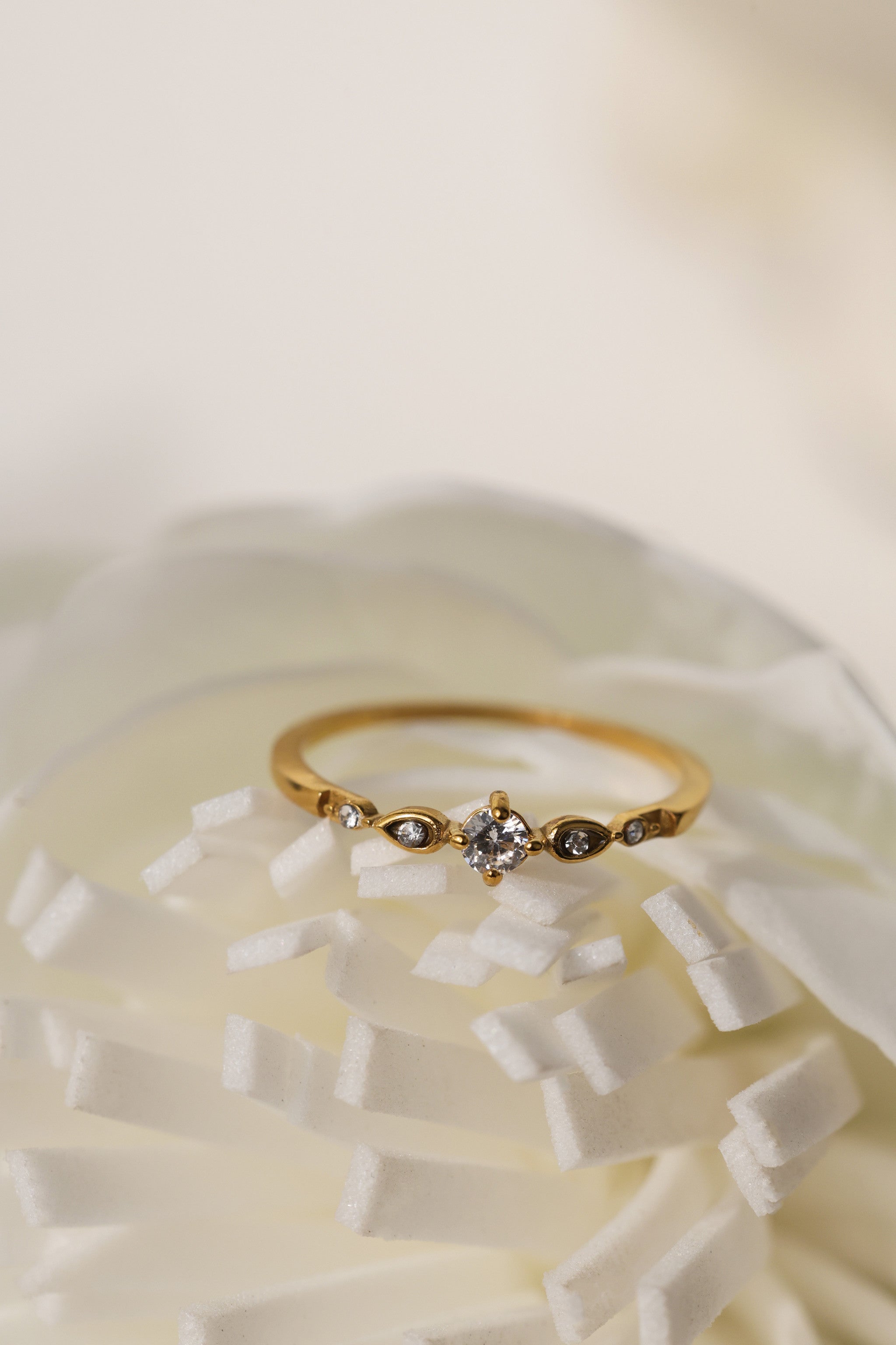 Colette vintage five stone ring in gold beside a white flower