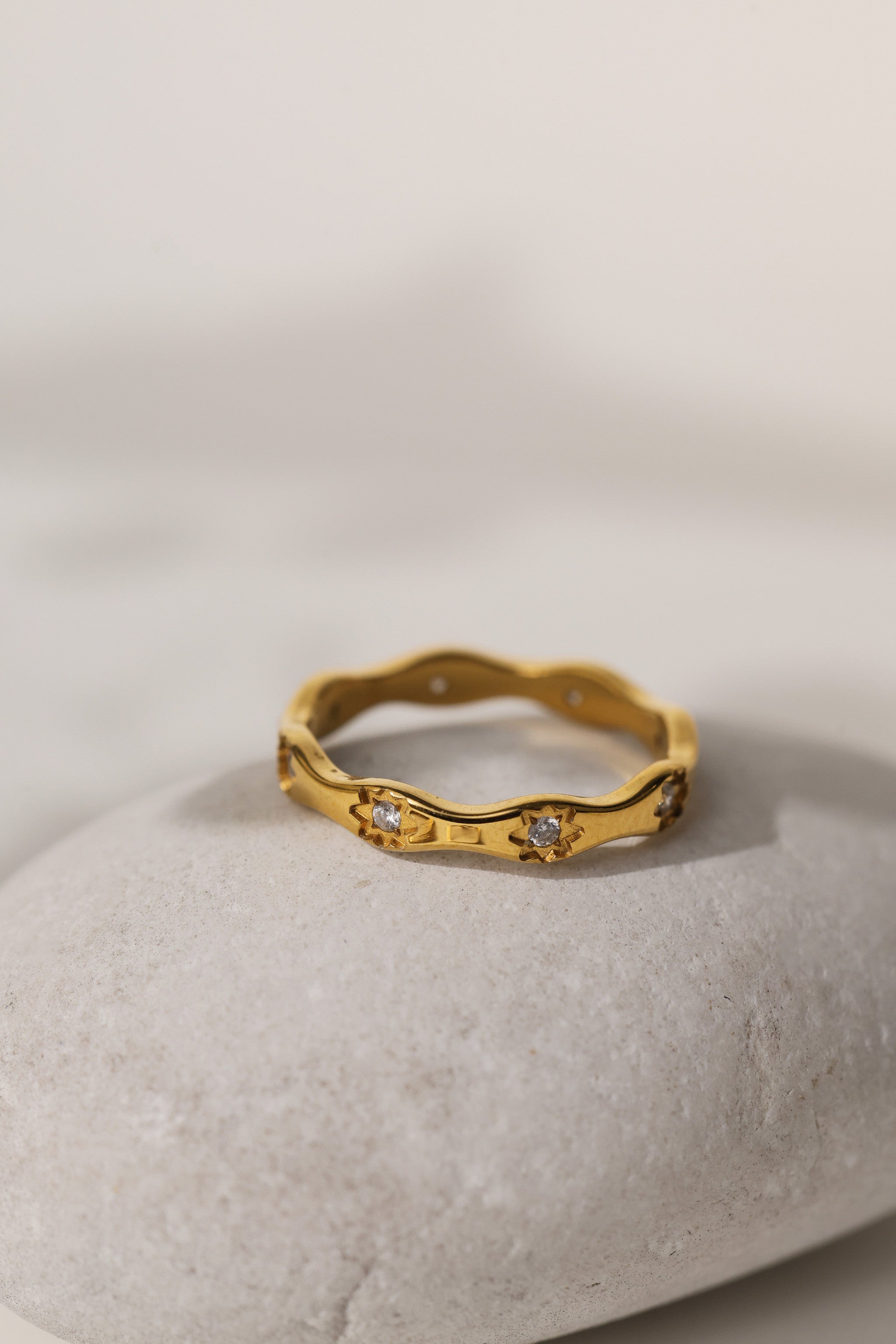 Delphine star eternity band in gold resting on a pale stone